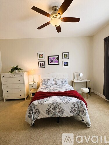 A bedroom with a bed, dresser, and ceiling fan.