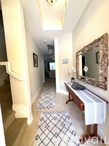 A hallway with a bench, mirror, and tiled floor.