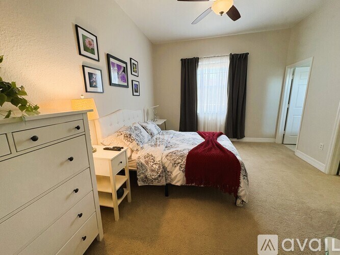 A bedroom with a bed, dresser, and ceiling fan.