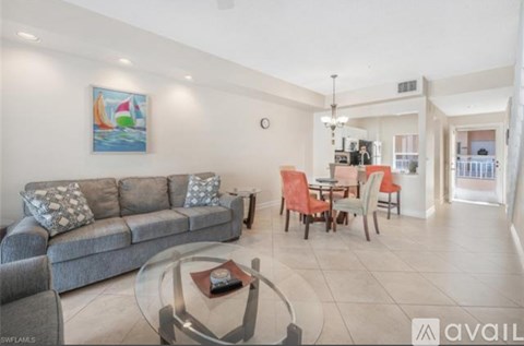 A living room with a grey couch, a glass coffee table, and a painting on the wall.