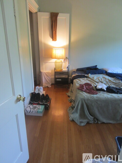 A bedroom with a bed, nightstand, and a suitcase on the floor.