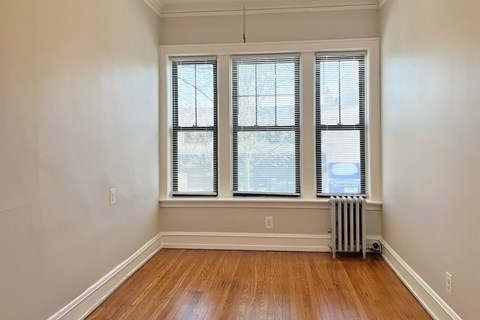 A room with a window and a radiator on the floor.