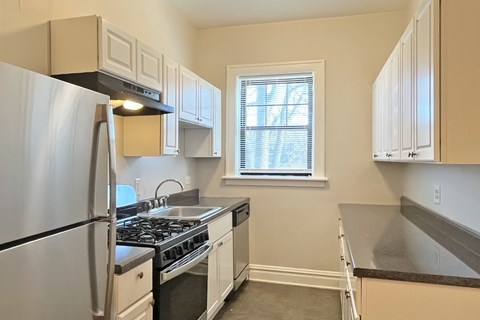 A kitchen with a stainless steel refrigerator and white cabinets.