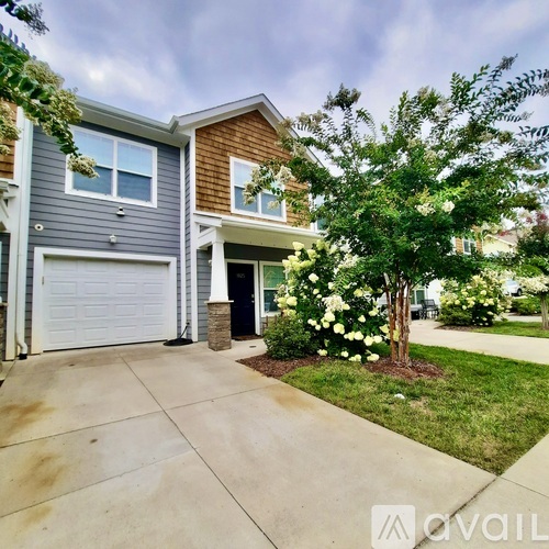 A house with a garage and a tree with white flowers in front.