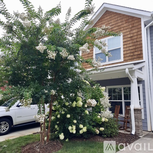 A white car is parked in front of a house.