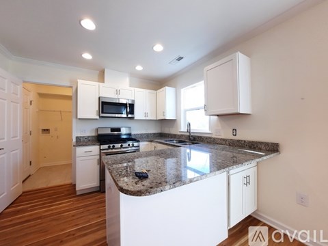 A kitchen with white cabinets and a granite countertop.