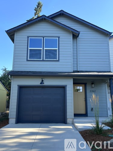 A two-story house with a garage door and a small window on the second floor.