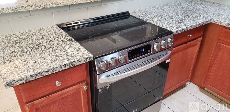 A black stove top oven with silver knobs and handles is built into a kitchen island with a granite counter top.