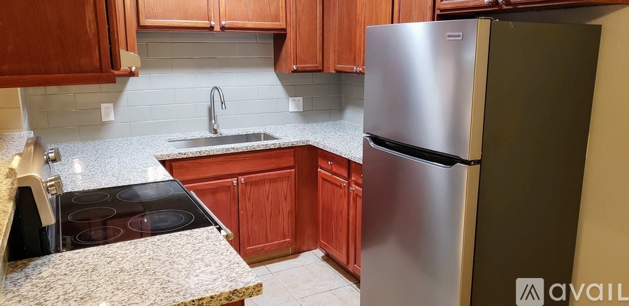 A kitchen with a stove top oven, sink, and refrigerator.