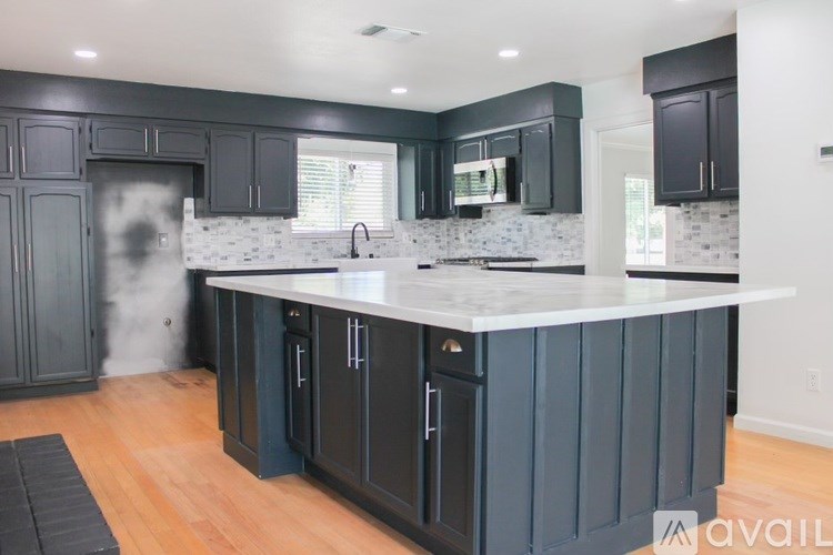 A kitchen with dark grey cabinets and a white countertop.