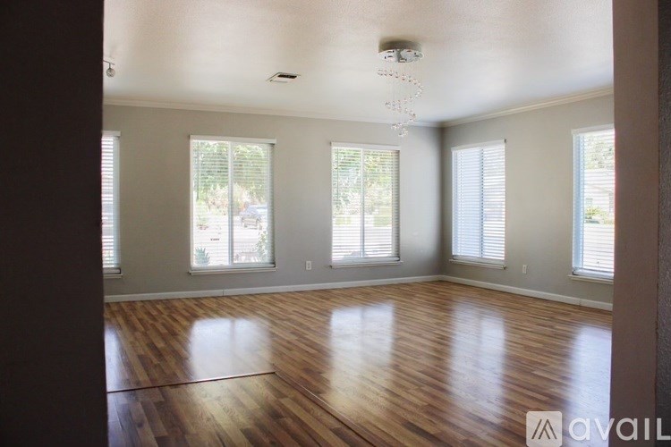 A room with wooden floors and windows covered with blinds.