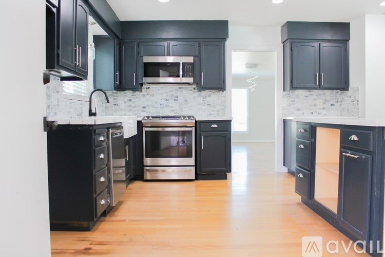 A kitchen with black cabinets and a white backsplash.