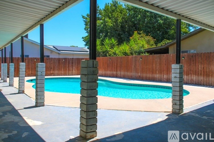 A pool surrounded by a wooden fence and concrete pillars.