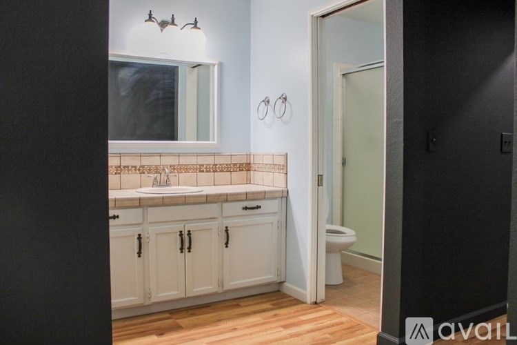 A bathroom with a toilet, sink, and cabinets.
