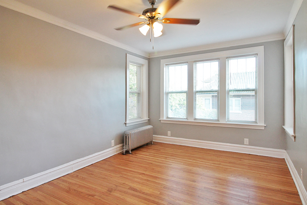 an empty room with wood floors and a ceiling fan