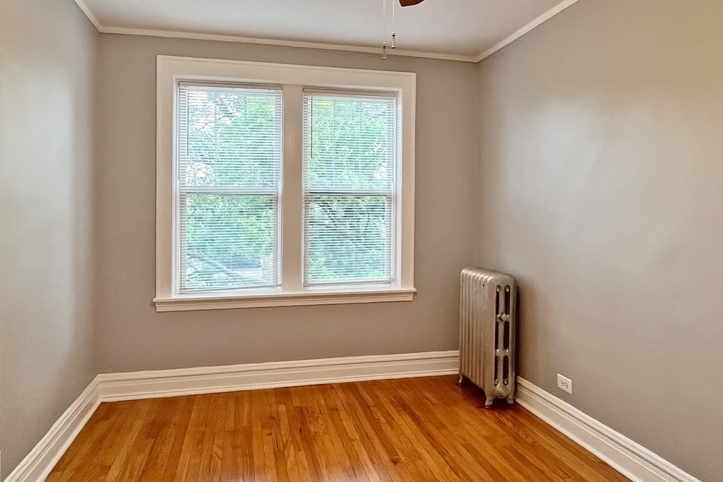 A room with a window and a radiator on the floor.