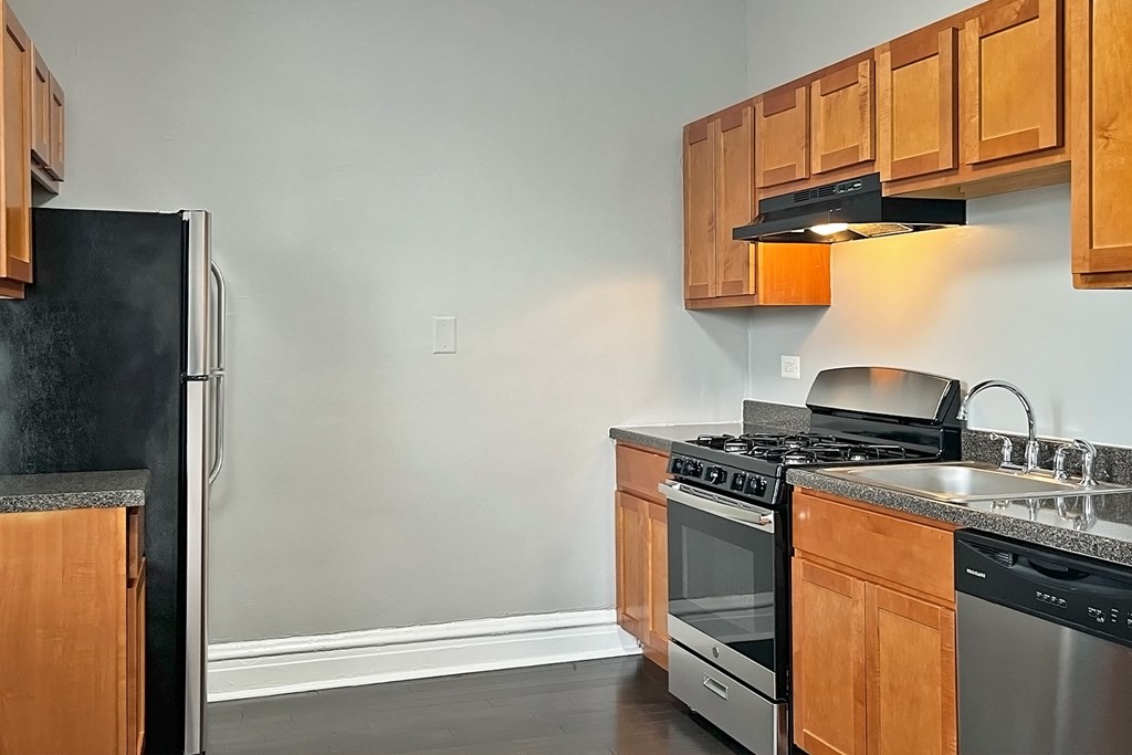 A kitchen with a black refrigerator and stainless steel appliances.