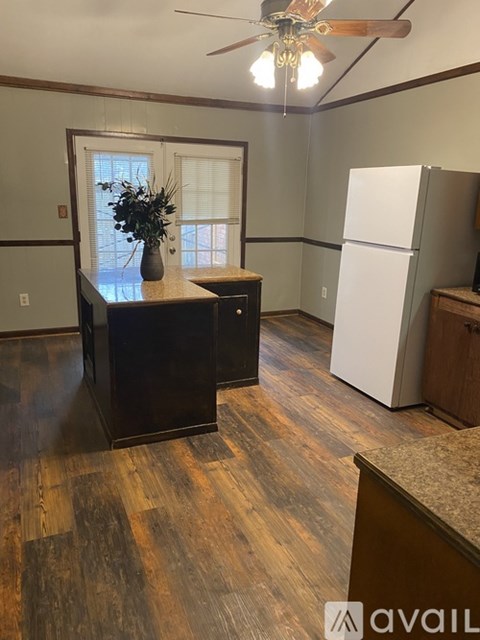 A kitchen with a wooden floor and a ceiling fan.