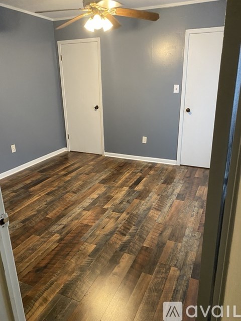 A room with wooden flooring and two white doors.