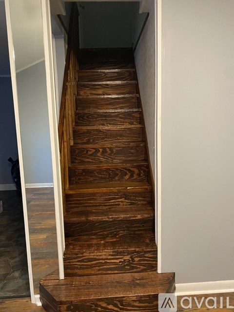 A long flight of wooden stairs leading to a white wall.