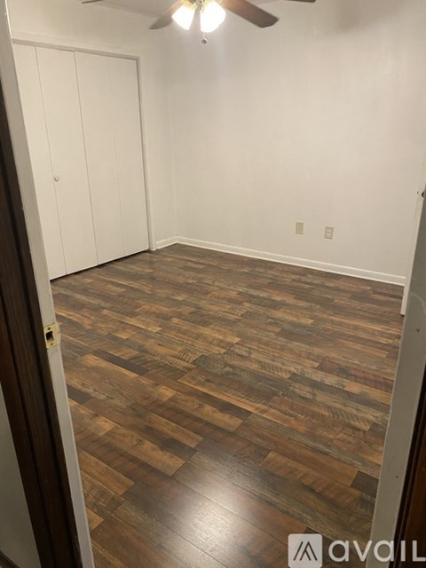 A room with wooden flooring and a ceiling fan.
