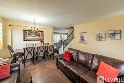 A living room with a brown leather couch and a chandelier.