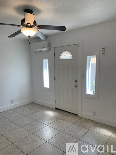 A room with a ceiling fan and a door.
