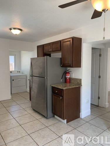 A kitchen with a refrigerator and a fan.