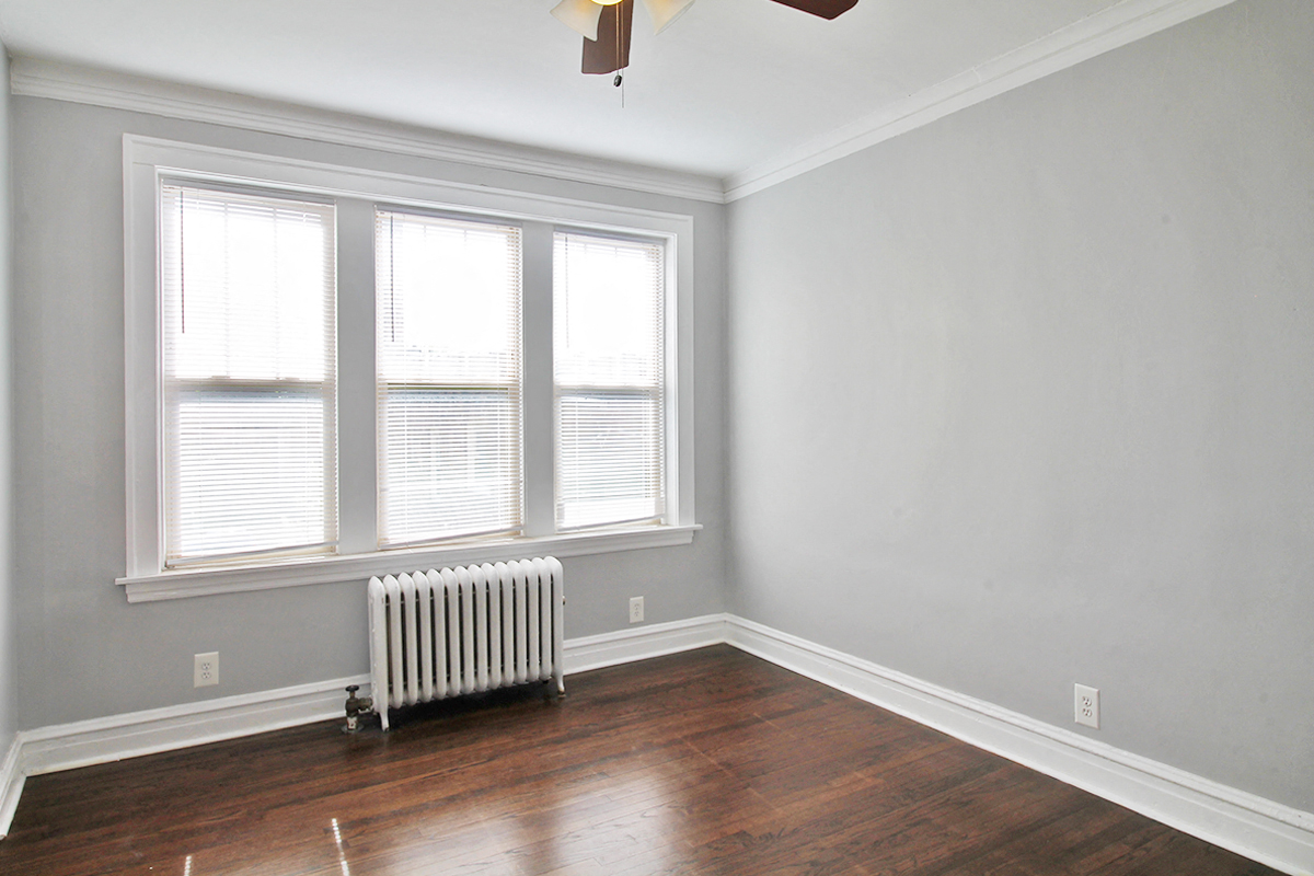 an empty room with a radiator and three windows