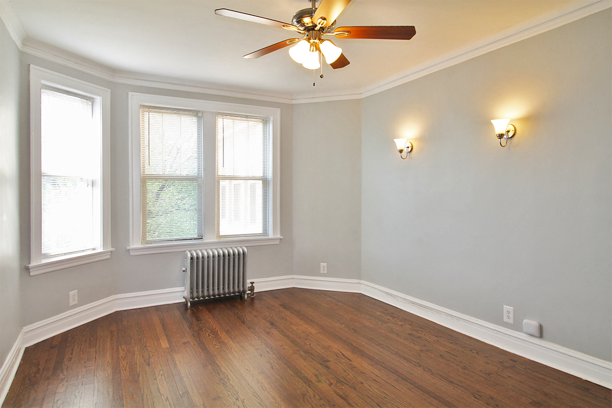 an empty room with a ceiling fan and three windows
