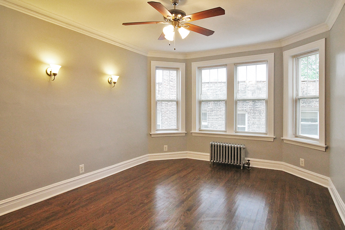 an empty living room with a ceiling fan and windows