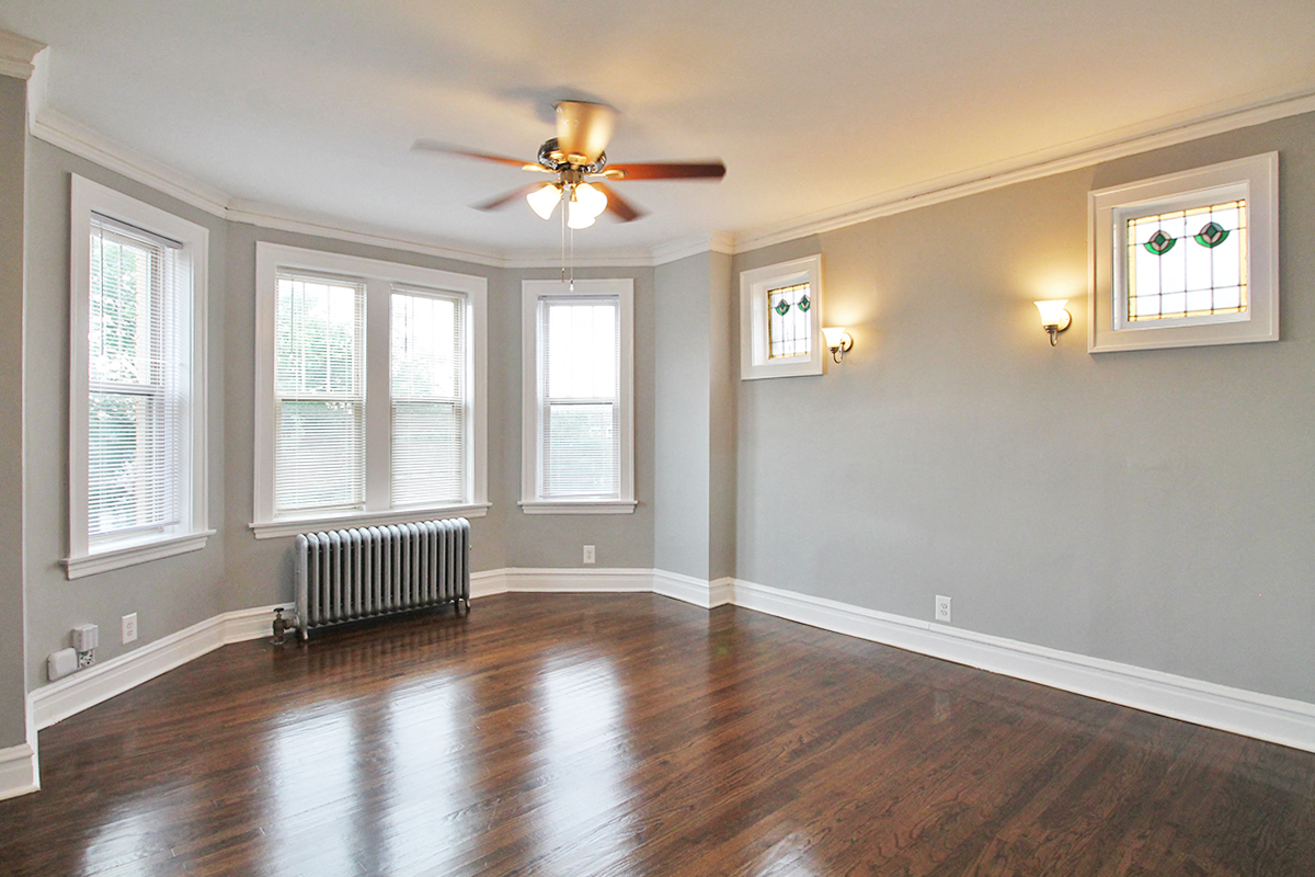 an empty living room with wood floors and a ceiling fan