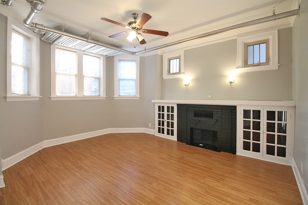 an empty living room with a ceiling fan and a fireplace
