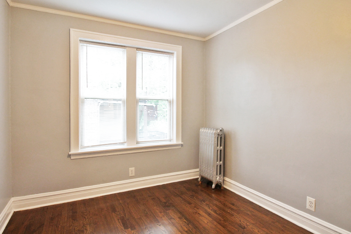 an empty room with a radiator and two windows