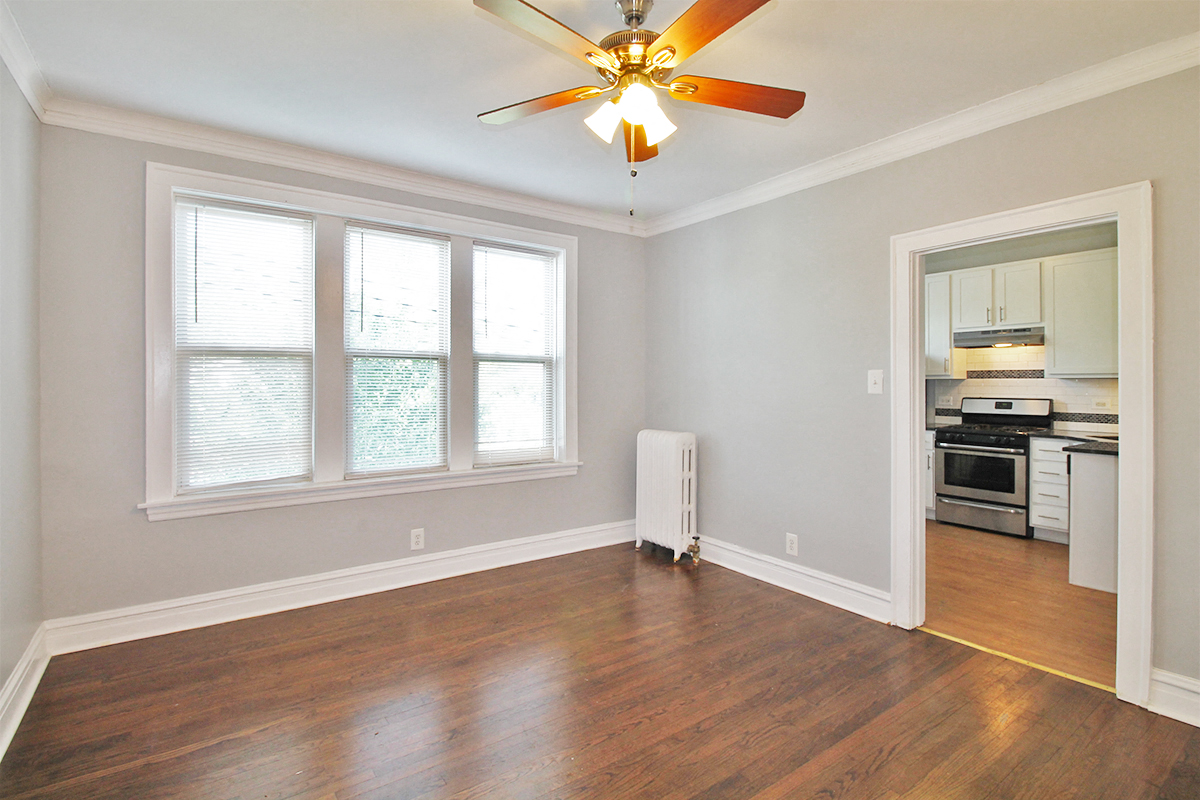 an empty living room with wood floors and a ceiling fan
