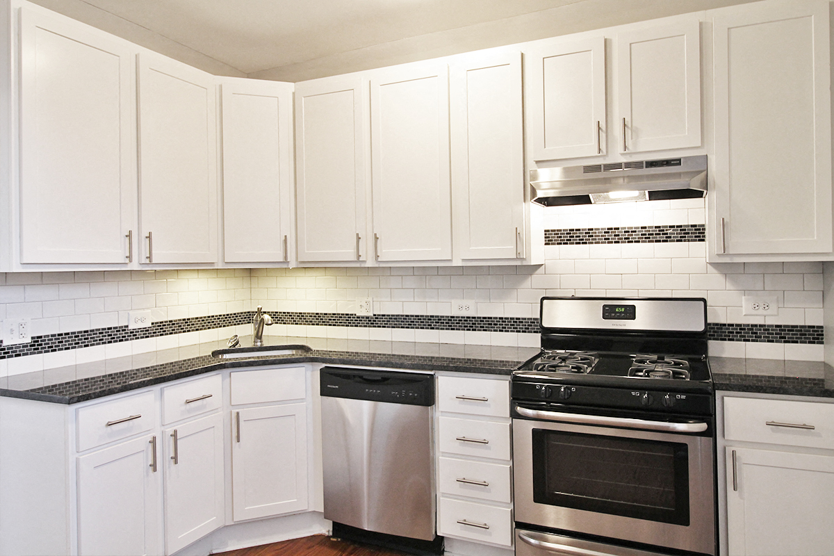 a white kitchen with stainless steel appliances and white cabinets
