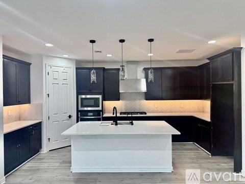 A modern kitchen with a white island and black cabinets.