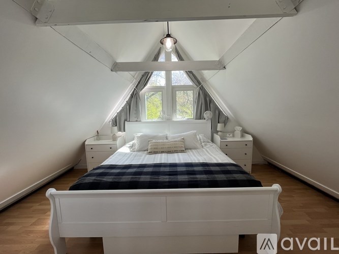 A bedroom with a bed, nightstands, and a window.