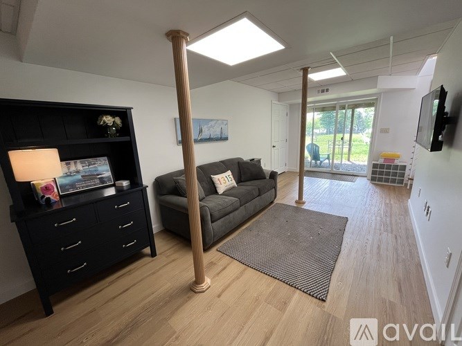 A living room with a grey couch and a black bookshelf.
