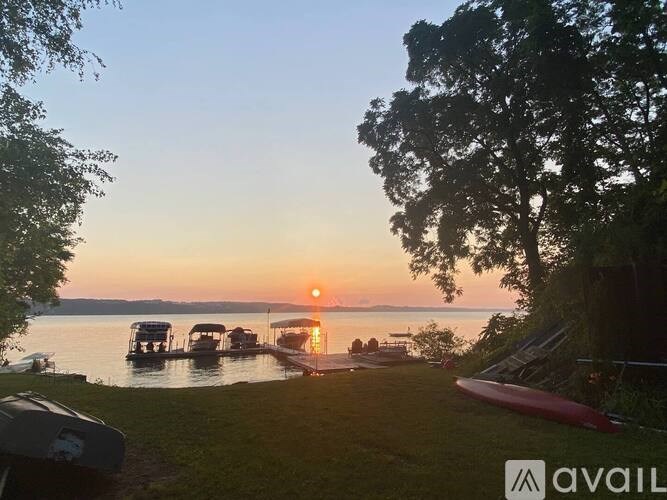 A serene lakeside scene with boats docked at a pier during sunset.