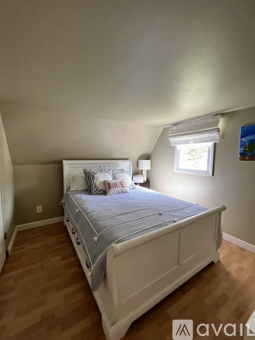 A bedroom with a bed, nightstand, and window.