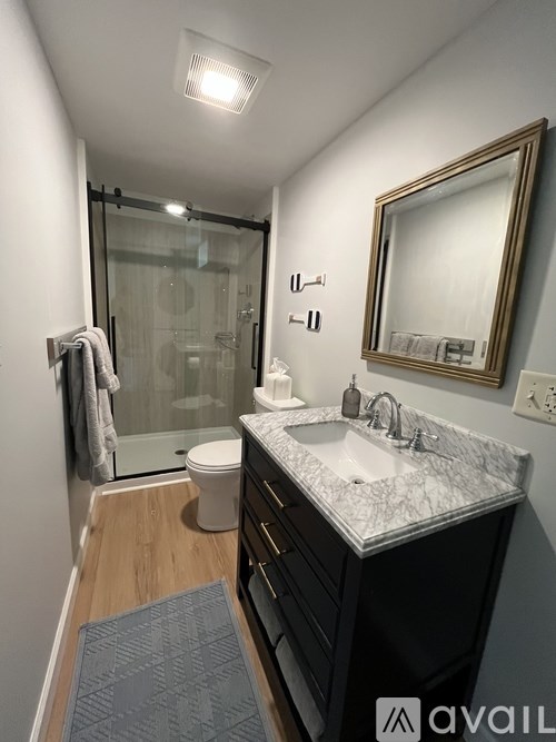 A bathroom with a marble countertop and a mirror above it.