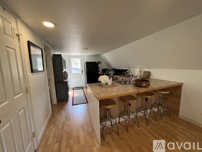 A kitchen with a bar stool and a fridge.