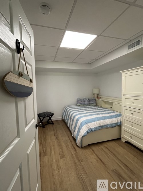 A bedroom with a bed, dresser, and a wall-mounted light fixture.