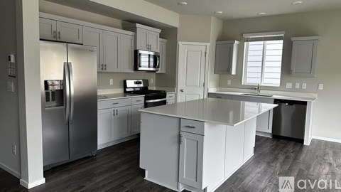 A kitchen with white cabinets and a stainless steel refrigerator.