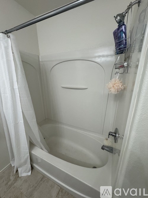 A white bathtub with a white shower curtain and a towel hanging on the side.