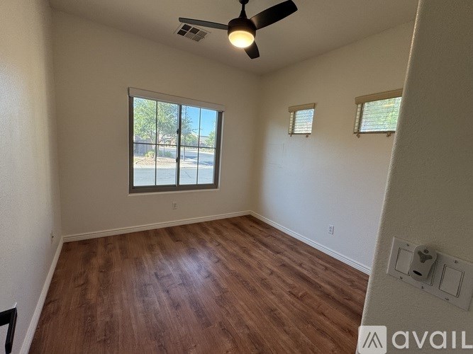 A room with a ceiling fan and wooden flooring.
