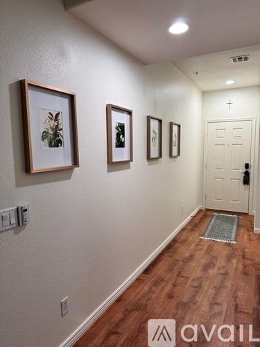 A hallway with a white door and three pictures on the wall.