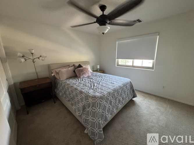 A bedroom with a bed, ceiling fan, and carpeted floor.