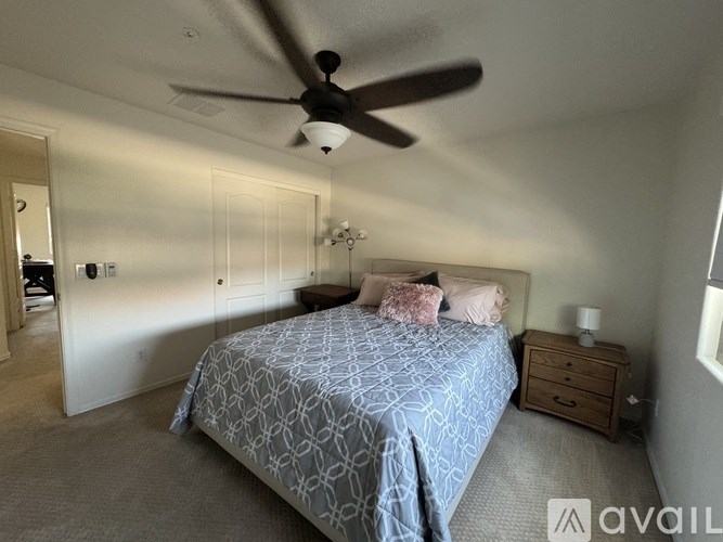 A bedroom with a bed, dresser, and ceiling fan.